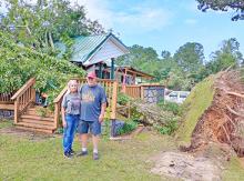 Lonnie and Clyda Garrison stand in front of what’s left of their  home after a storm Saturday afternoon, July 18, sent a large tree crashing into it.